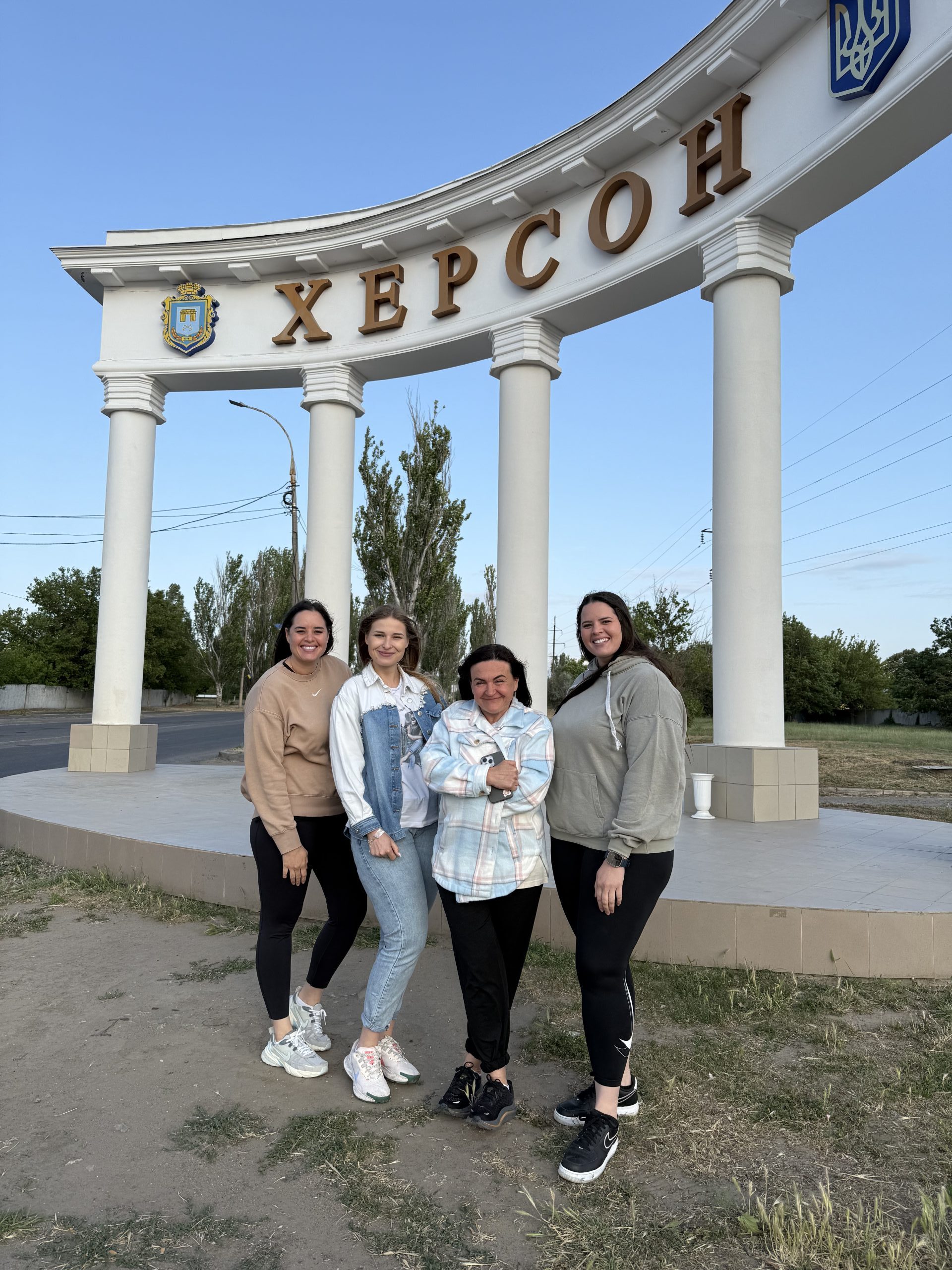 IMG_5143 Seven women lined up smiling with boxes in the background.