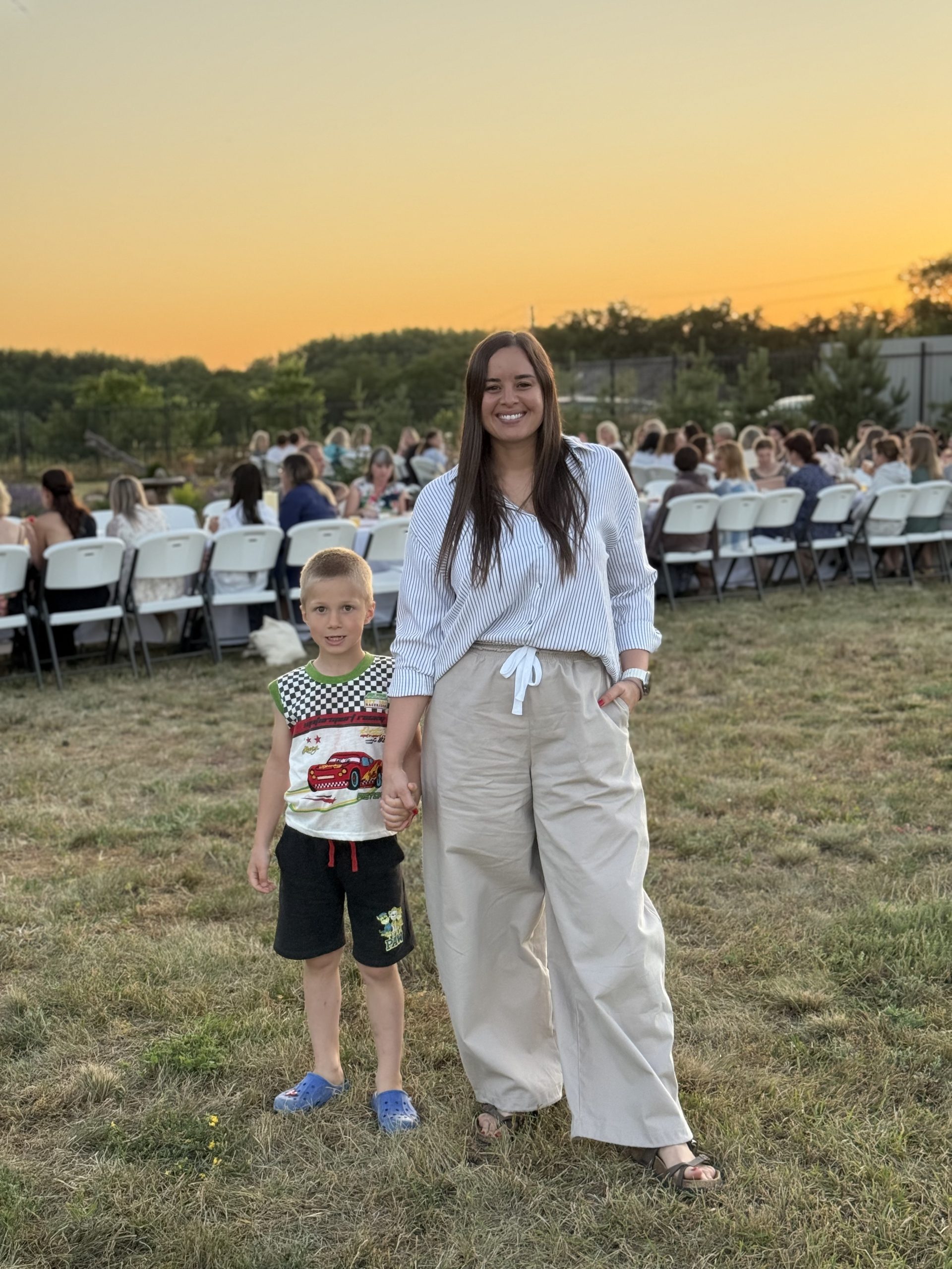 IMG_5711 Woman carrying child on her back in grassy field.