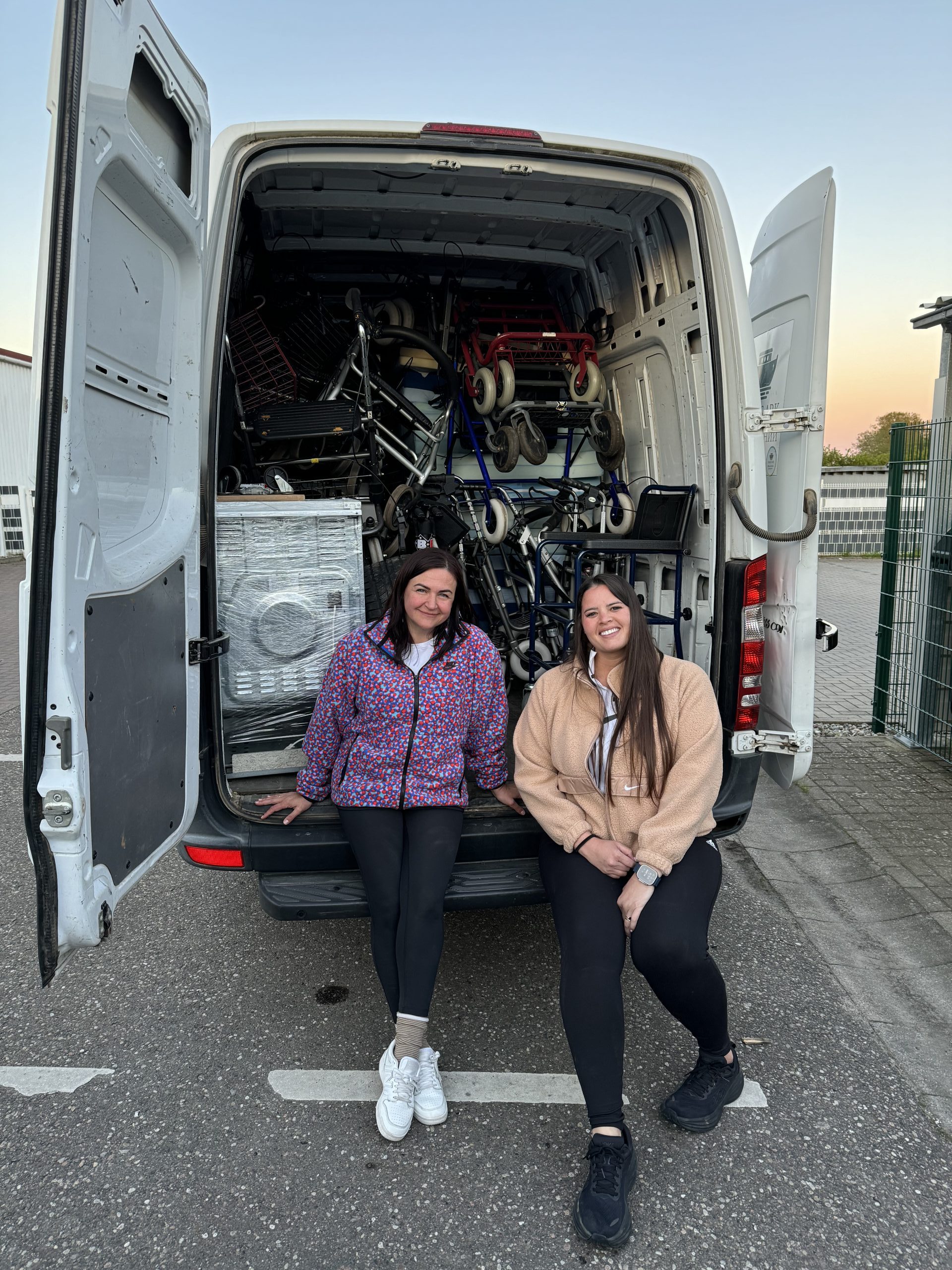 Two women carrying buckets down a dirt road.